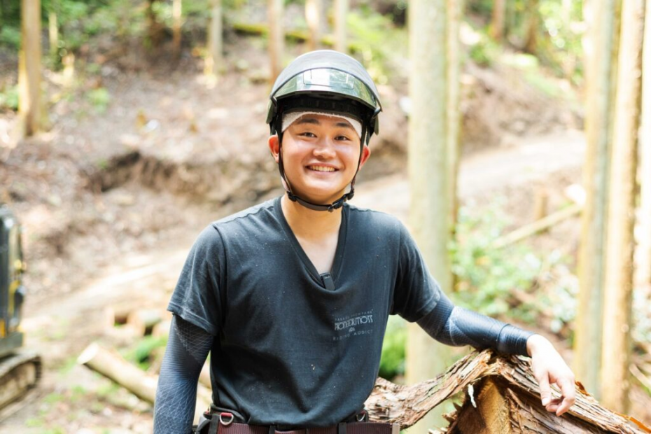山の中で林業用ヘルメットを被って微笑む中屋敷さん
